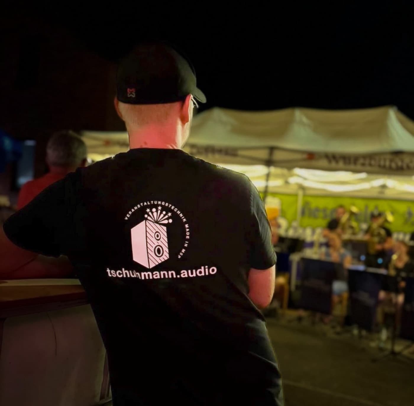 Mitarbeiter im tschuhmann.audio-Shirt vor der Bühne bei einer Abendveranstaltung